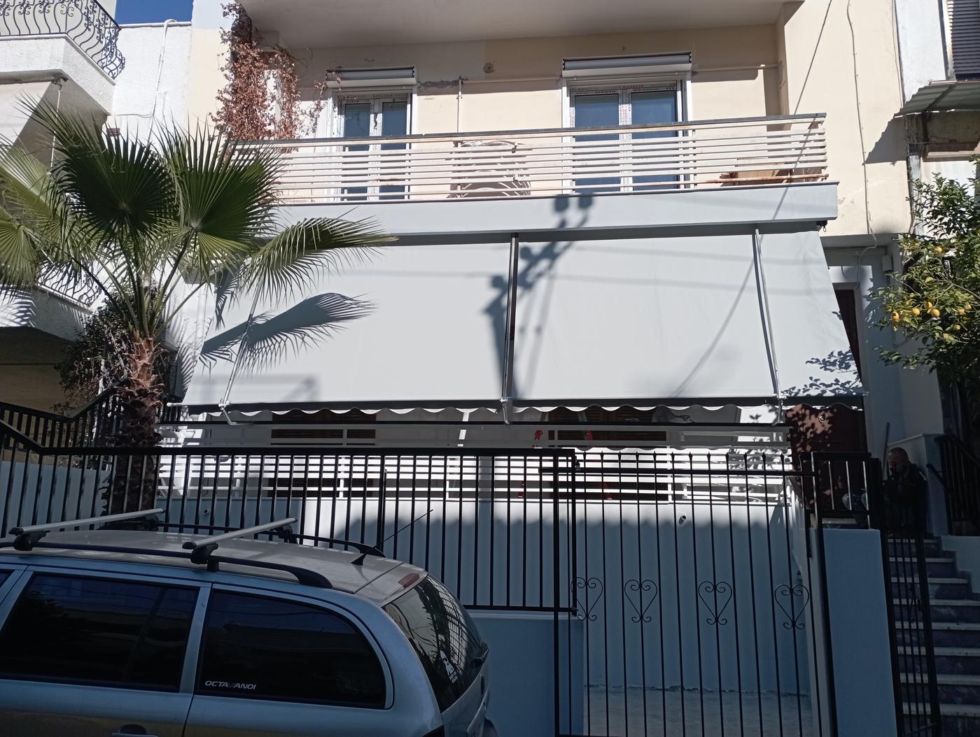 Γκρι τέντες σε κατοικία με φοίνικα